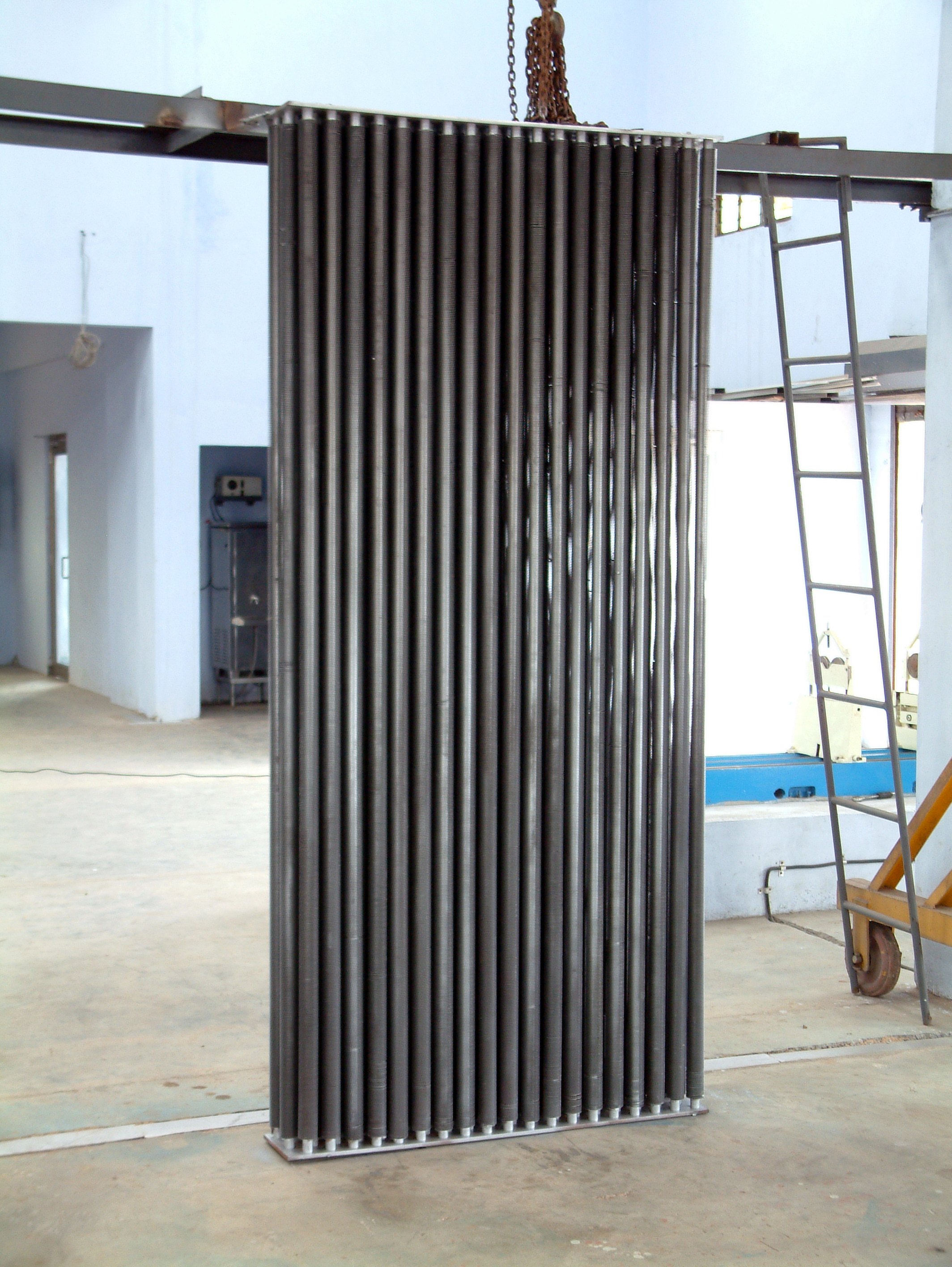 A finned-tube heat exchanger bank lifted on the shop hoist